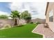 Spacious backyard featuring artificial turf, stone landscaping, privacy wall, and diverse vegetation at 607 W Tenia Trl, San Tan Valley, AZ 85140