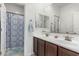 Bathroom featuring double sink vanity, stylish mirrors, and a shower with a decorative curtain at 607 W Tenia Trl, San Tan Valley, AZ 85140