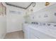 Well-lit laundry room with modern washer, dryer, utility sink, and decorative shelving at 607 W Tenia Trl, San Tan Valley, AZ 85140