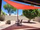 Relaxing patio area with comfortable seating under a shade sail, surrounded by desert landscaping at 656 W Devon Ct, Gilbert, AZ 85233