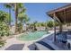 Backyard pool area with lush landscaping, including palm trees and a rock waterfall at 656 W Devon Ct, Gilbert, AZ 85233