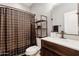 Bathroom with wood vanity, white countertop, and tiled shower with decorative curtain at 7305 W Darrel Rd, Laveen, AZ 85339