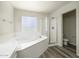A bright bathroom featuring a soaking tub, separate glass shower, and mosaic glass block window at 8723 E Kiowa Ave, Mesa, AZ 85209