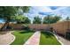 Serene backyard with manicured artificial grass, a brick paver walkway, and privacy fencing at 10377 W Yukon Dr, Peoria, AZ 85382