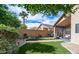 Beautifully landscaped backyard featuring lush artificial turf, a covered patio, and privacy fence at 10377 W Yukon Dr, Peoria, AZ 85382