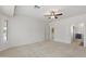 Bedroom features neutral carpet, a ceiling fan, a bright window, and a doorway to another room at 13414 W San Pablo Dr, Sun City West, AZ 85375