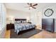 Comfortable bedroom featuring hardwood floors, ceiling fan, and ensuite bathroom entrance at 16165 W Vale Dr, Goodyear, AZ 85395