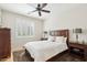 Cozy bedroom with a ceiling fan, plush rug, a window with plantation shutters, and classic furnishings at 16165 W Vale Dr, Goodyear, AZ 85395
