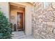 Inviting entryway with a solid wood door, stone accents, and lush plants at 16165 W Vale Dr, Goodyear, AZ 85395