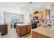 A kitchen boasts warm wood cabinetry, granite counters, an island, tile flooring, and a dining area with ample natural light at 16165 W Vale Dr, Goodyear, AZ 85395