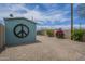 Backyard featuring a small shed with a peace sign, desert landscaping, and a clear blue sky at 1637 W University Dr, Mesa, AZ 85201