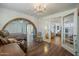 Bedroom with four-poster bed, hardwood floors, brick archway, and adjoining room with chandelier at 1637 W University Dr, Mesa, AZ 85201