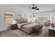 A serene main bedroom with carpet flooring, ceiling fan, and comfortable seating area by the windows at 1669 E Santa Fiore St, San Tan Valley, AZ 85140