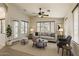 Bright living room features a ceiling fan, large windows, neutral tones, and comfortable seating, creating a welcoming atmosphere at 17617 W Corrine Dr, Surprise, AZ 85388