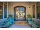 Elegant front entry features a black-framed glass door, sidelights, and potted plants on a brick walkway at 19947 N 94Th Way, Scottsdale, AZ 85255