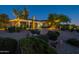 Beautiful desert landscaping enhances this home with a circular driveway and attached garages at dusk at 19947 N 94Th Way, Scottsdale, AZ 85255