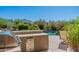 Built-in stainless steel grill and prep area next to a lush backyard with a swimming pool at 19947 N 94Th Way, Scottsdale, AZ 85255