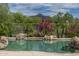 A tranquil pool surrounded by vibrant desert landscaping and natural rock features against a backdrop of scenic mountain views at 19947 N 94Th Way, Scottsdale, AZ 85255