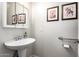 Cozy powder room featuring a pedestal sink with chrome hardware and framed mirror with decorative art at 33602 N Cobble Stone Dr, San Tan Valley, AZ 85143