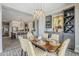 This dining room offers open kitchen access, bar storage, decorative art, a lovely chandelier, and yellow and white chairs at 35486 N Morello Dr, Queen Creek, AZ 85140