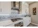 Modern kitchen with white cabinets, stylish backsplash, stainless hood and gas cooktop at 35486 N Morello Dr, Queen Creek, AZ 85140