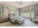 The main bedroom features a king bed, bedside tables, a bench, a ceiling fan, and window views of the backyard at 35486 N Morello Dr, Queen Creek, AZ 85140