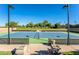 Well-maintained tennis court with new surface and seating and manicured landscape in the background at 35486 N Morello Dr, Queen Creek, AZ 85140
