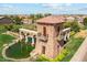 Aerial view of the Tortosa community entrance with a stone tower, water feature, and lush landscaping at 35941 W San Ildefanso Ave, Maricopa, AZ 85138