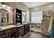Bathroom featuring dual sinks with dark wood cabinets, stone surround shower, and modern fixtures at 41215 N Lytham Ct, Phoenix, AZ 85086