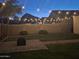 Backyard with grass, bushes, fence and hanging string lights above patio at 4595 W Foldwing Dr, San Tan Valley, AZ 85144