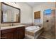 A well-lit bathroom showcases a tub, a shower and a granite topped dark-wood vanity at 4721 N Aldea W Rd, Litchfield Park, AZ 85340