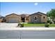 Charming single-story home with a two-car garage and stone accents, showcasing manicured landscaping and inviting curb appeal at 4721 N Aldea W Rd, Litchfield Park, AZ 85340