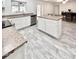 Open kitchen with white cabinetry, island, granite countertops, and wood-look tile floors at 4838 W Christine Cir, Glendale, AZ 85308