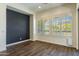 Bright living room featuring wood tile floors, plantation shutters, and a stylish accent wall at 70 E Kennedia Dr, Queen Creek, AZ 85140