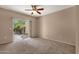 A carpeted bedroom featuring a ceiling fan and sliding glass door leading to an outdoor space at 7101 W Beardsley Rd # 1502, Glendale, AZ 85308