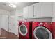 Well-lit laundry room featuring bright red washer and dryer units and extra storage cabinets at 725 W Beth Dr, Phoenix, AZ 85041