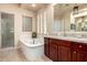 Bright bathroom with a soaking tub, glass block window, and vanity with cherry wood cabinets at 816 W Sycamore Ct, Litchfield Park, AZ 85340