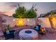 A lovely stone patio and firepit area feature accent lighting and comfortable seating under a star-filled sky at 816 W Sycamore Ct, Litchfield Park, AZ 85340
