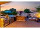 Wonderful outdoor kitchen with stainless steel grill, bar, and stone accents; patio firepit nearby at 816 W Sycamore Ct, Litchfield Park, AZ 85340