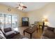 Comfortable living room featuring plush seating, wood-look floors, a ceiling fan, and sliding glass doors at 10619 W Loma Blanca Dr, Sun City, AZ 85351