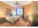 A cozy bedroom featuring a bed with decorative pillows, a ceiling fan, and a view through the windows at 12826 W La Vina Dr, Sun City West, AZ 85375