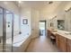 A spacious main bathroom featuring a tub, shower, dual sink vanity and door to the main bedroom at 12826 W La Vina Dr, Sun City West, AZ 85375