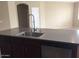 Kitchen island features a sink with a modern faucet, countertop, and stainless steel dishwasher at 14977 W Charter Oak Rd, Surprise, AZ 85379