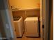 Functional laundry room with a washer, dryer, and built-in shelving for storage at 14977 W Charter Oak Rd, Surprise, AZ 85379