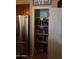 Walk-in pantry with organized shelving filled with various food items next to stainless steel refrigerator at 14977 W Charter Oak Rd, Surprise, AZ 85379