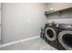 Modern laundry room with a front loading washer and dryer and wire shelving at 16551 W Winston Dr, Goodyear, AZ 85338