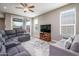 Open living room with gray sofas, a ceiling fan, and a sliding glass door to the patio at 16551 W Winston Dr, Goodyear, AZ 85338