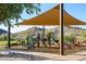 Community playground featuring slides, climbing structures, and shade covering with mountain views in background at 16551 W Winston Dr, Goodyear, AZ 85338