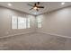 Bright bedroom featuring large windows, a ceiling fan, and plush carpeting at 17531 W Fetlock Trl, Surprise, AZ 85387
