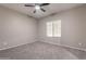Neutral bedroom features carpeted floors, a ceiling fan, and a window for natural light at 17531 W Fetlock Trl, Surprise, AZ 85387